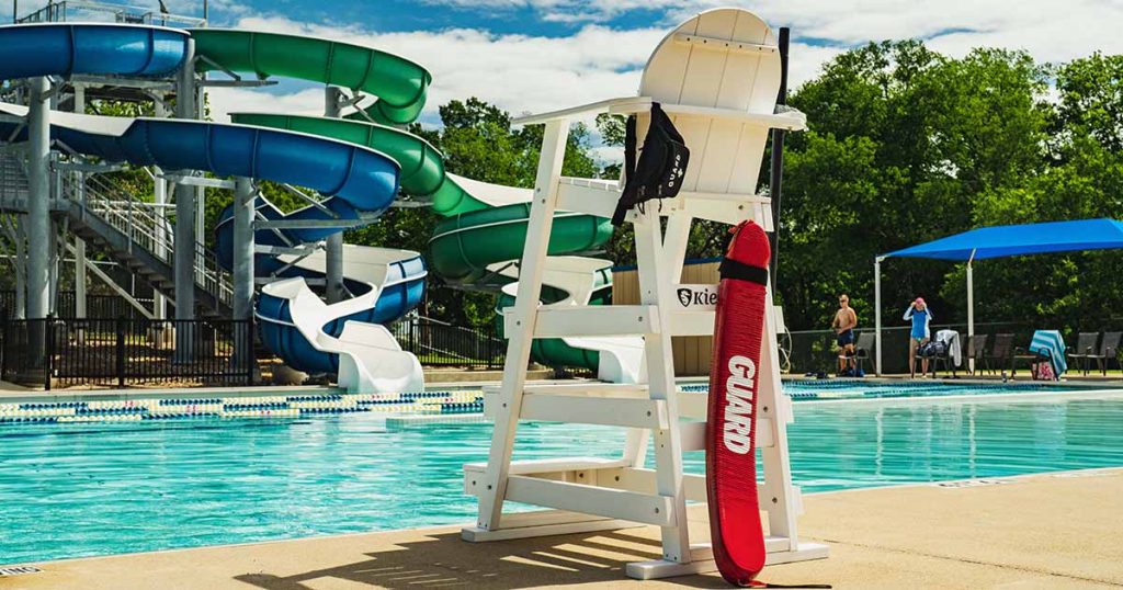 View of the Bryan Aquatic Center with the slides and the lifeguard chair with a safety flotation device.