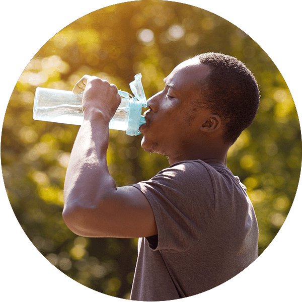 man standing outdoors on a sunny hot day drinking water