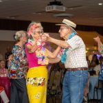 Senior adults couples dancing dressed in luau themed attire