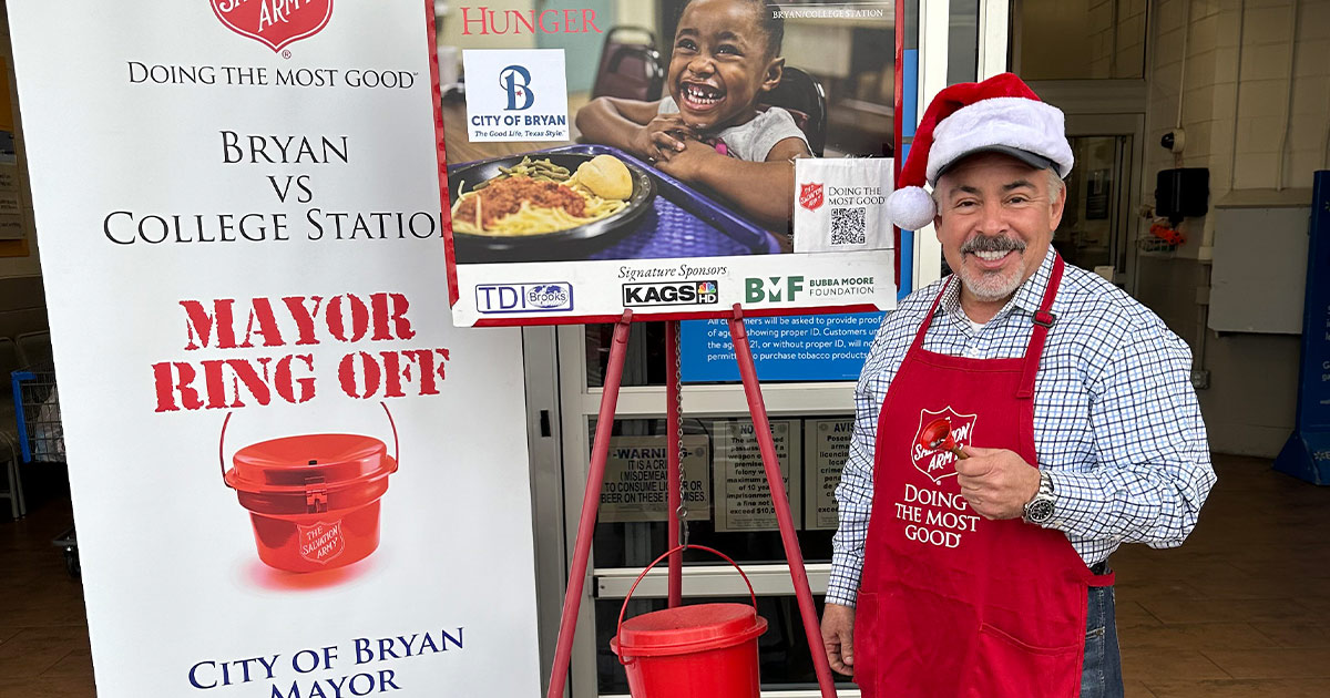 Mayor Bobby Gutierrez ringing a bell in front of a Salvation Army donation stand