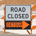 Road closed and detour sign set up on a road under construction