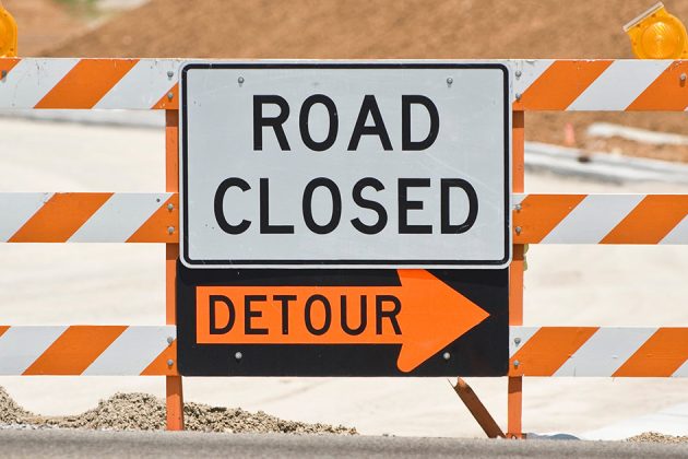 Road closed and detour sign set up on a road under construction