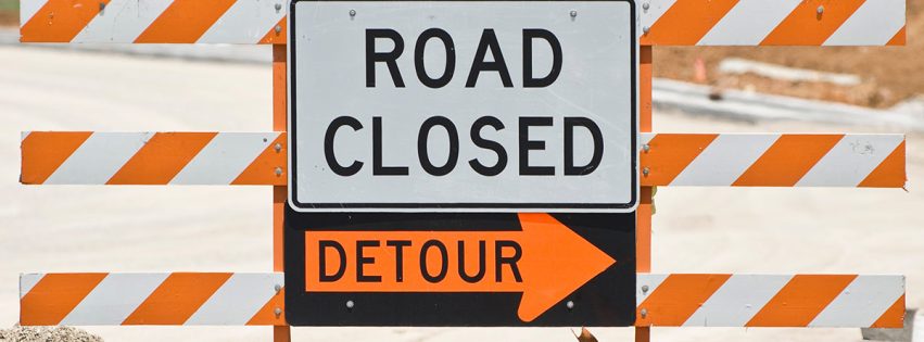 Road closed and detour sign set up on a road under construction