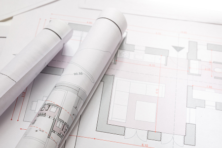 rolls of printed site review blueprint plans laying on a table