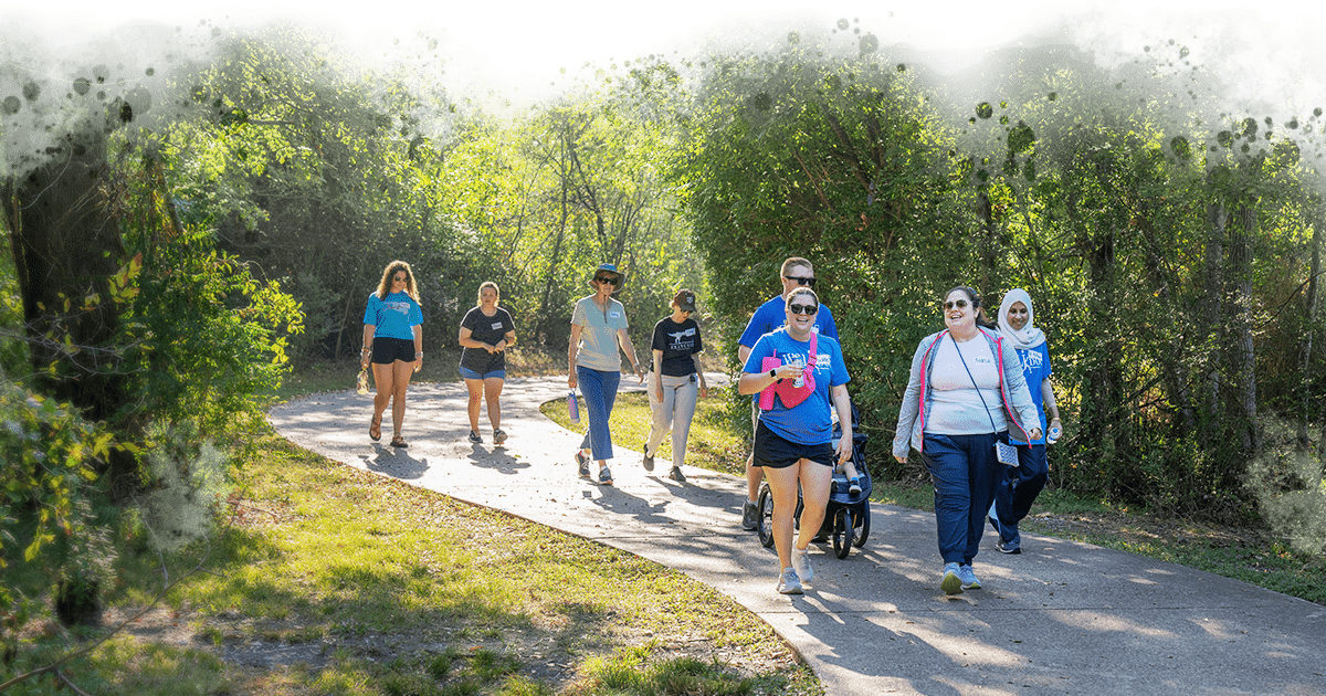 group of people walking down a park path smiling