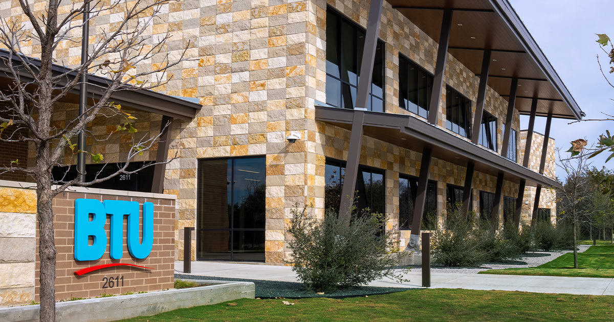 brick sign with colorful BTU logo in front of the new BTU facility building in the background