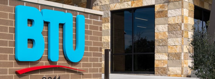 closeup of BTU brick sign with logo and the new facility building in the background