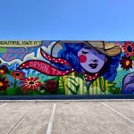 colorful mural on the side of a building featuring a cowgirl holding flowers in a pop art style