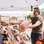 outdoor art booth vendor handing a customer their purchase