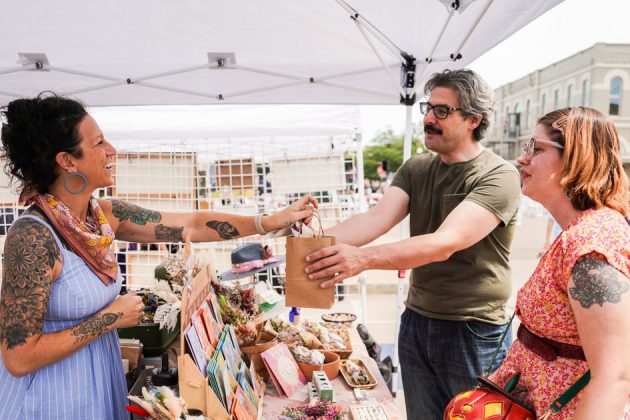 outdoor art booth vendor handing a customer their purchase