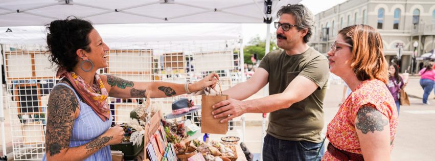 outdoor art booth vendor handing a customer their purchase