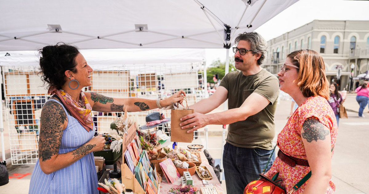 outdoor art booth vendor handing a customer their purchase