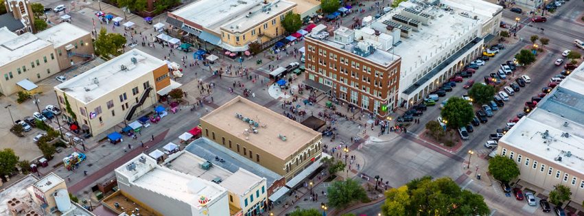 aerial image of downtown Bryan during an event with many pedestrians and parked vehicles