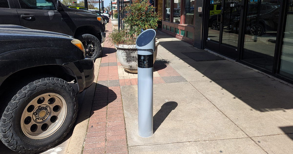 monitoring device mounted on a concrete pole near the curb of downtown Bryan street near parked cars