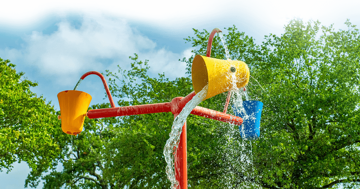 colorful buckets mounted on a pole splashing and dumping water in an outdoor water feature